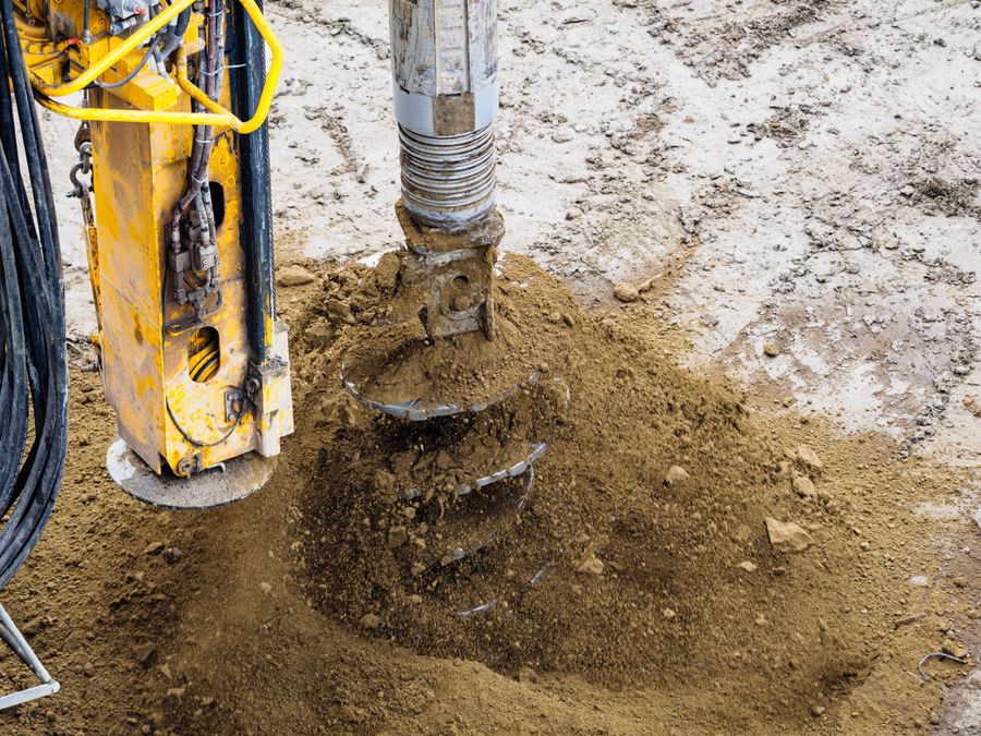 Drilling auger boring into brown soil at a construction site