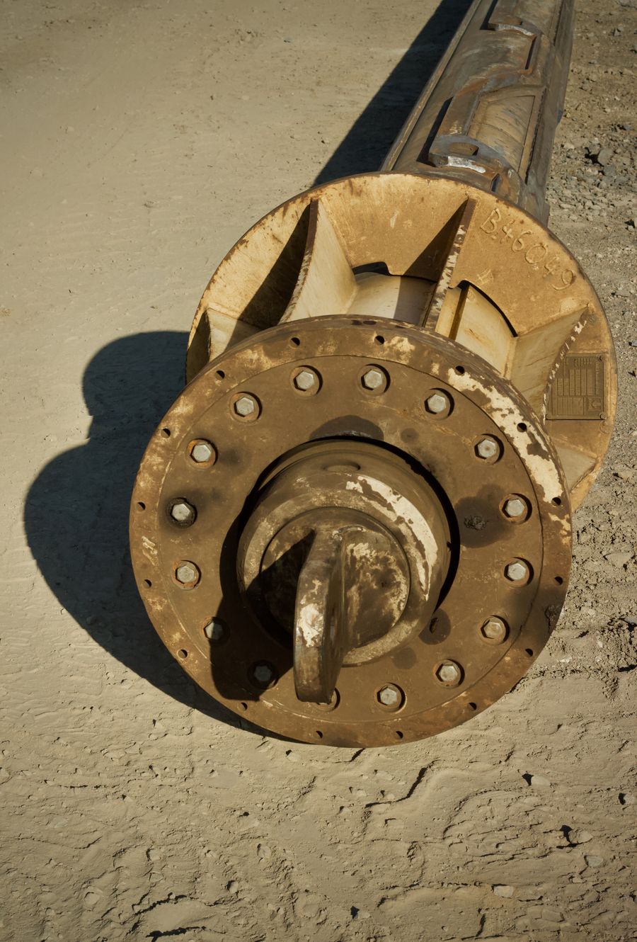 Close-up of a heavy-duty drilling auger bit resting on the ground